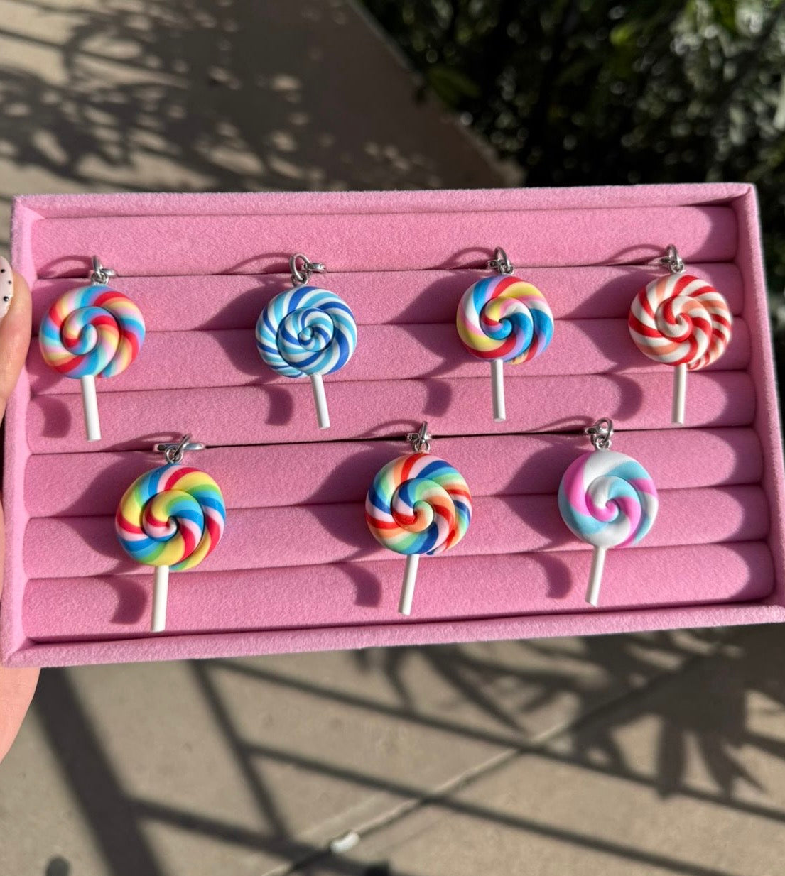 Colgante para celular Circus Swirl Charmie de Build a Caze, accesorio decorativo en forma de paleta con diseño de espiral multicolor y estilo arcoíris para teléfonos móviles.