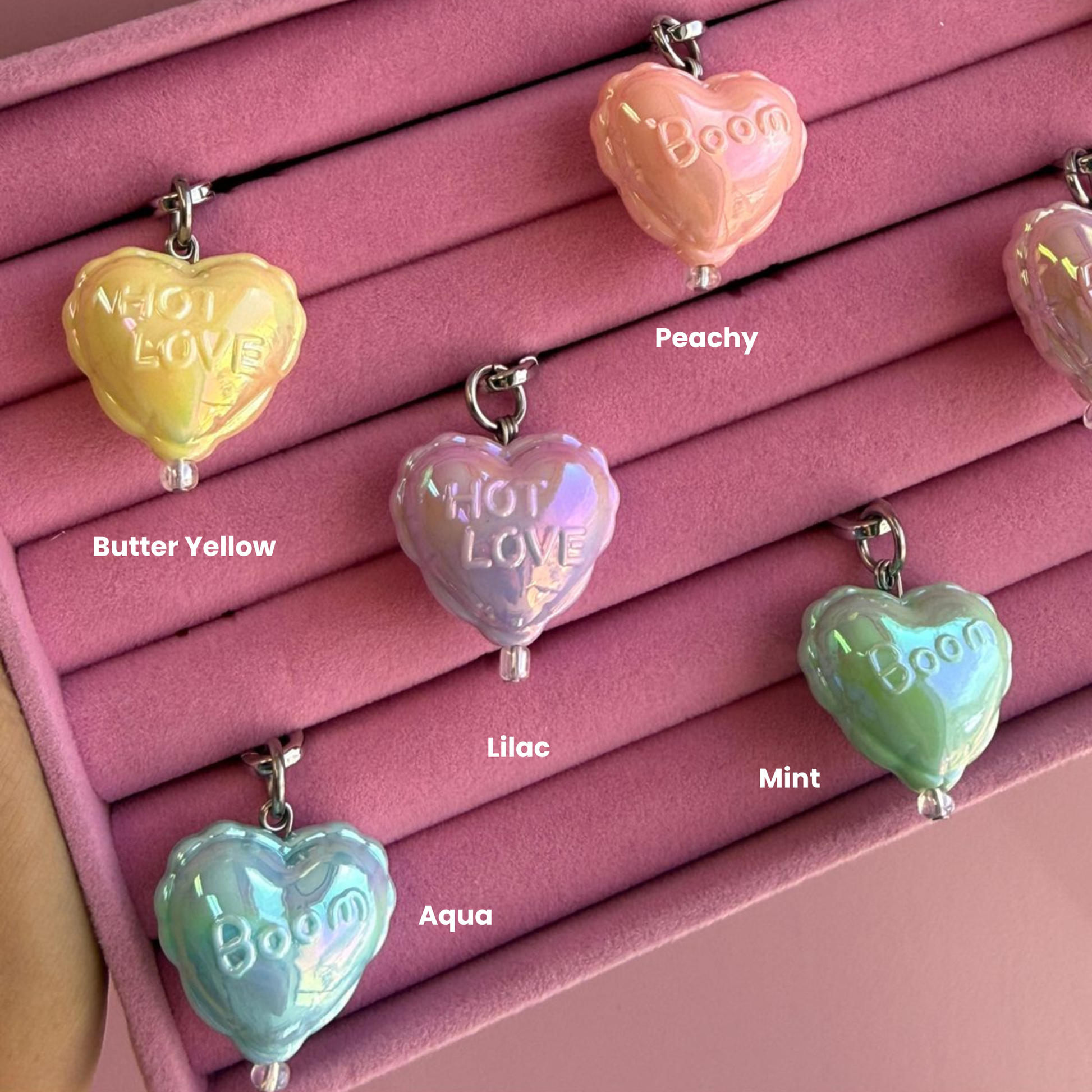 Un charm butter-yellow accesorio colgante de corazón sujeto a un celular - Build A Caze.