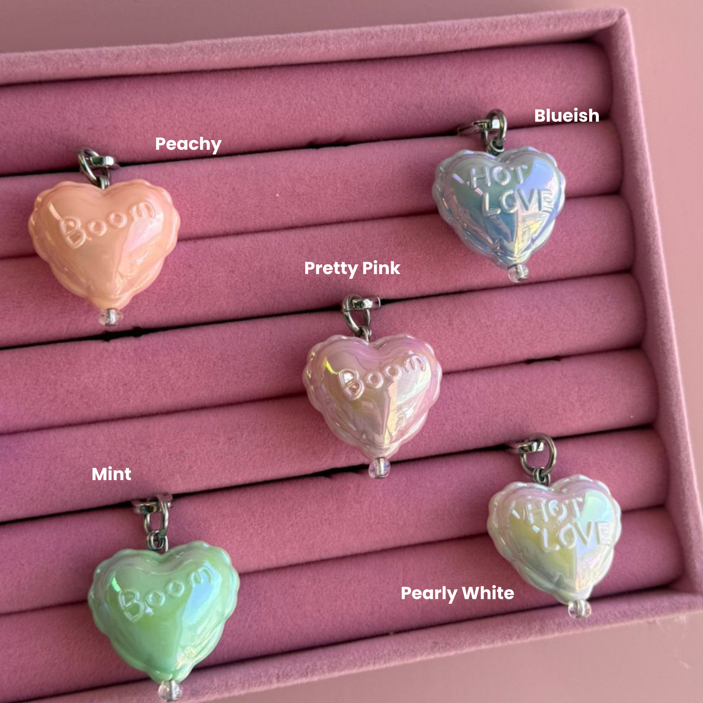 Un charm accesorio colgante Pretty Pink con forma de globo de corazón sujeto a un celular - Build A Caze.