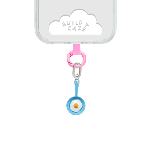 Un charm y accesorio colgante Blue Sunny Side Up Charmie en color azul sujeto a un celular - Build A Caze