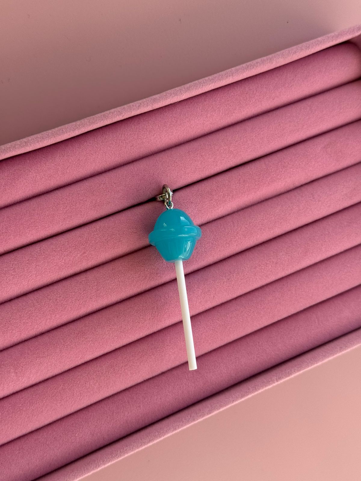 Un charm y accesorio colgante Blueberry Pop Charmie en color azul sujeto a un celular - Build A Caze