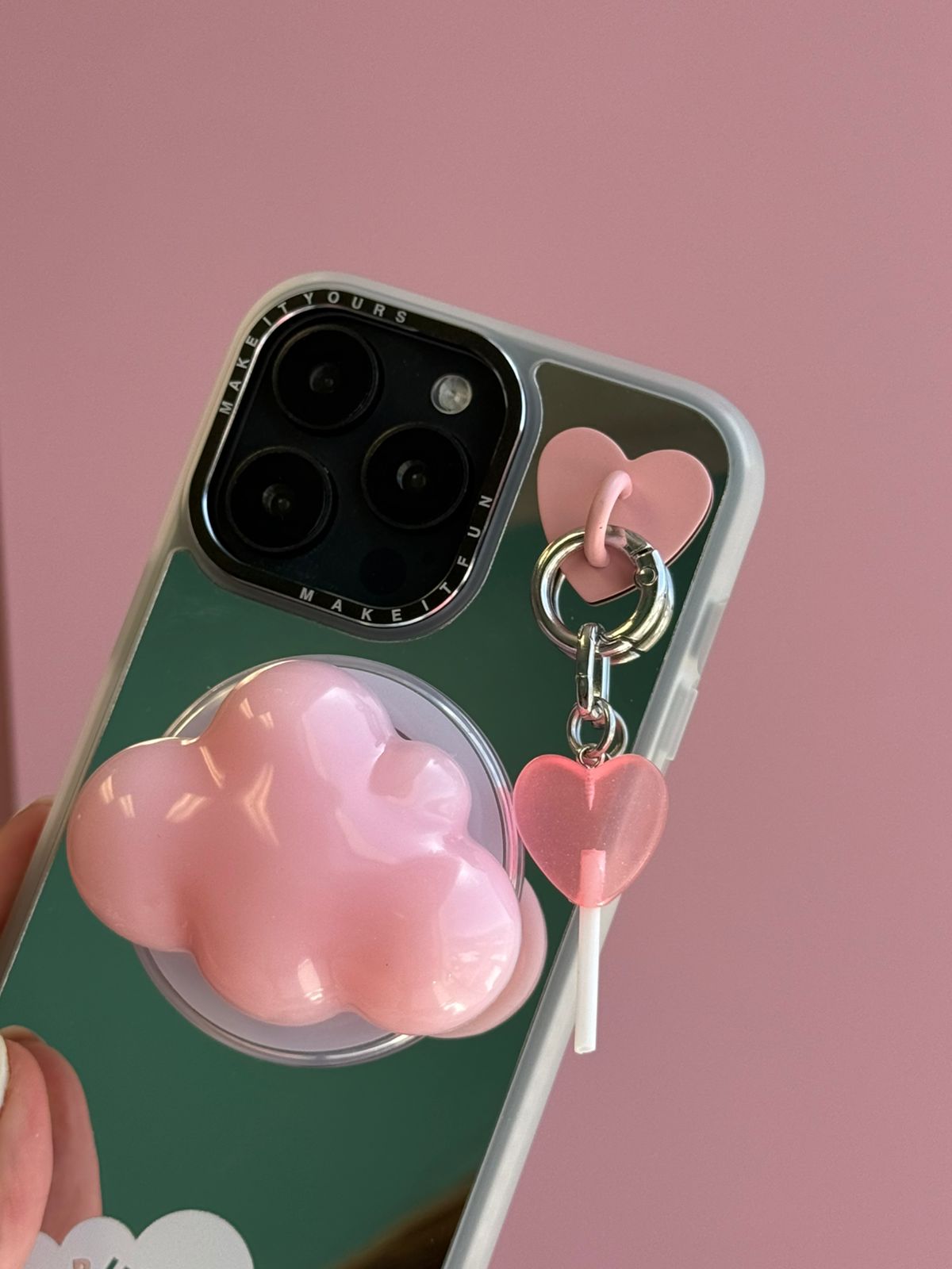 Un charm y accesorio colgante Coral Pink Lollie Pop Charmie en color rosa sujeto a un celular - Build A Caze