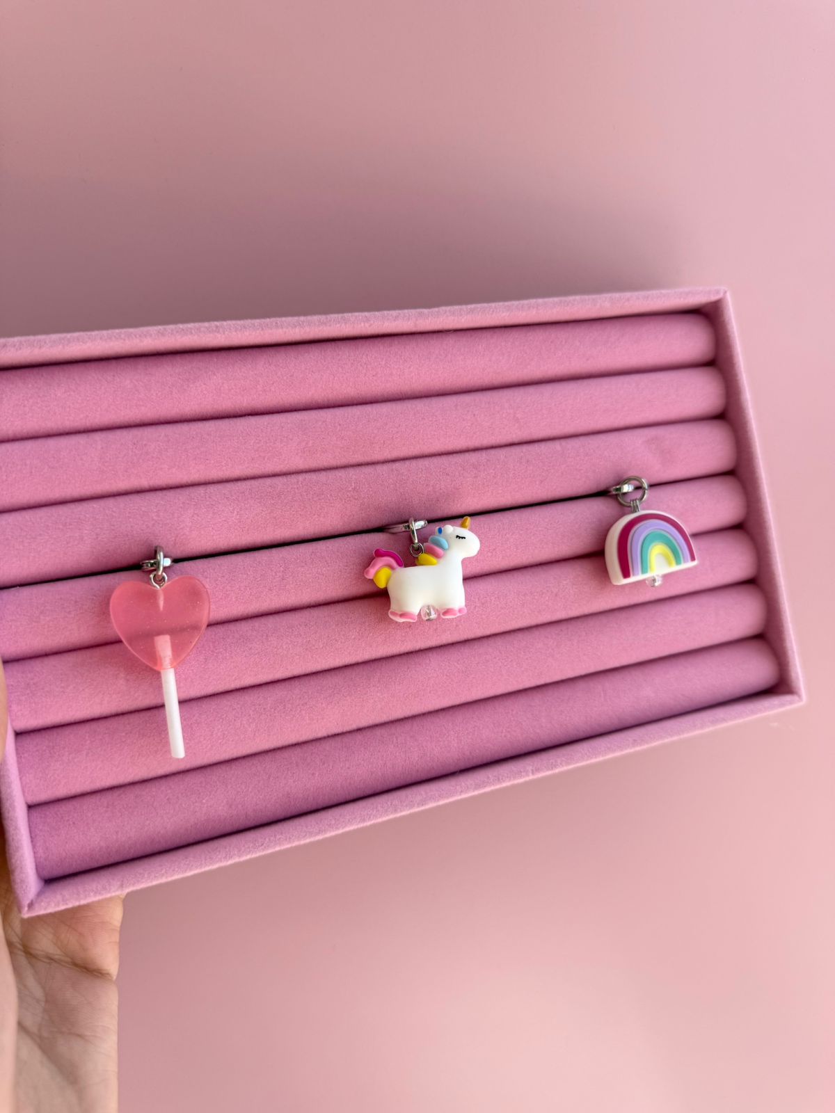 Un charm y accesorio colgante Coral Pink Lollie Pop Charmie en color rosa sujeto a un celular - Build A Caze
