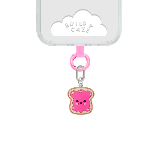 Un charm y accesorio colgante Jammy Toastie Charmie en color marrón y rosa sujeto a un celular - Build A Caze
